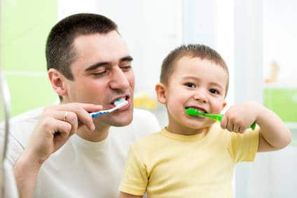 father and son brushing teeth